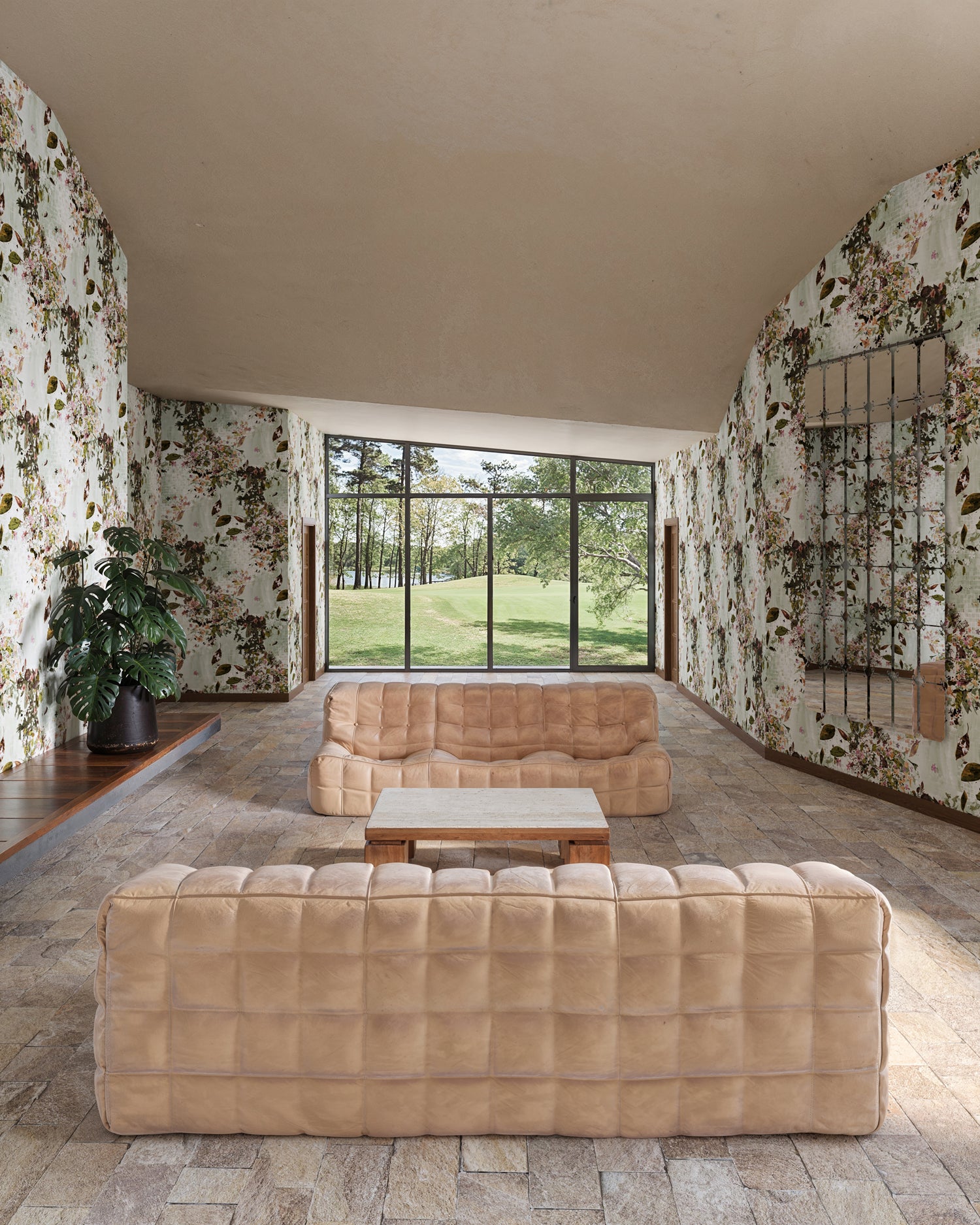 Modern living room with beige sofas and a large window overlooking greenery.