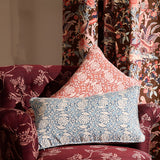 Decorative pillows on a floral-patterned armchair with floral-fauna printed curtains.
