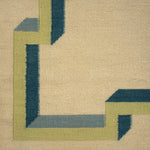Close-up of a geometric patterned rug with green and blue lines on a beige background