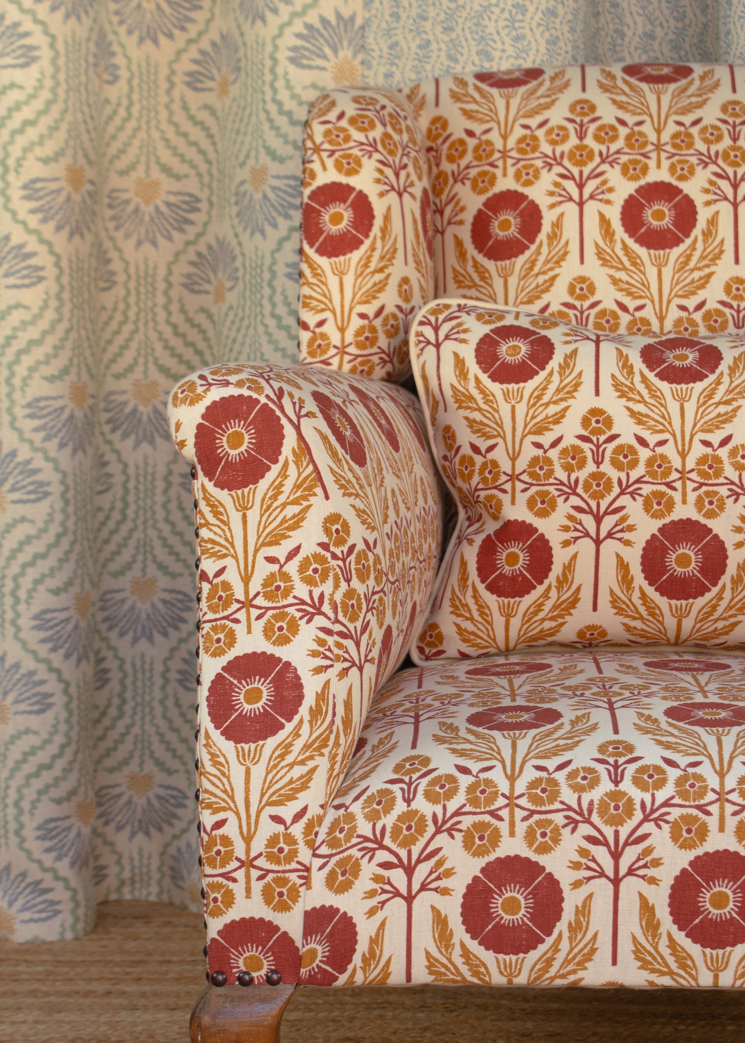 Detail of an upholstered chair in a floral pattern in orange and red on cream