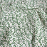Draped printed linen in a wavy floral stripe design in green on white. 