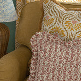 Tan side chair with floral printed accent pillows in red and ochre yellow. 