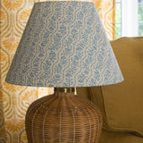 Rattan table lamp with a blue and white floral stripe shade. 