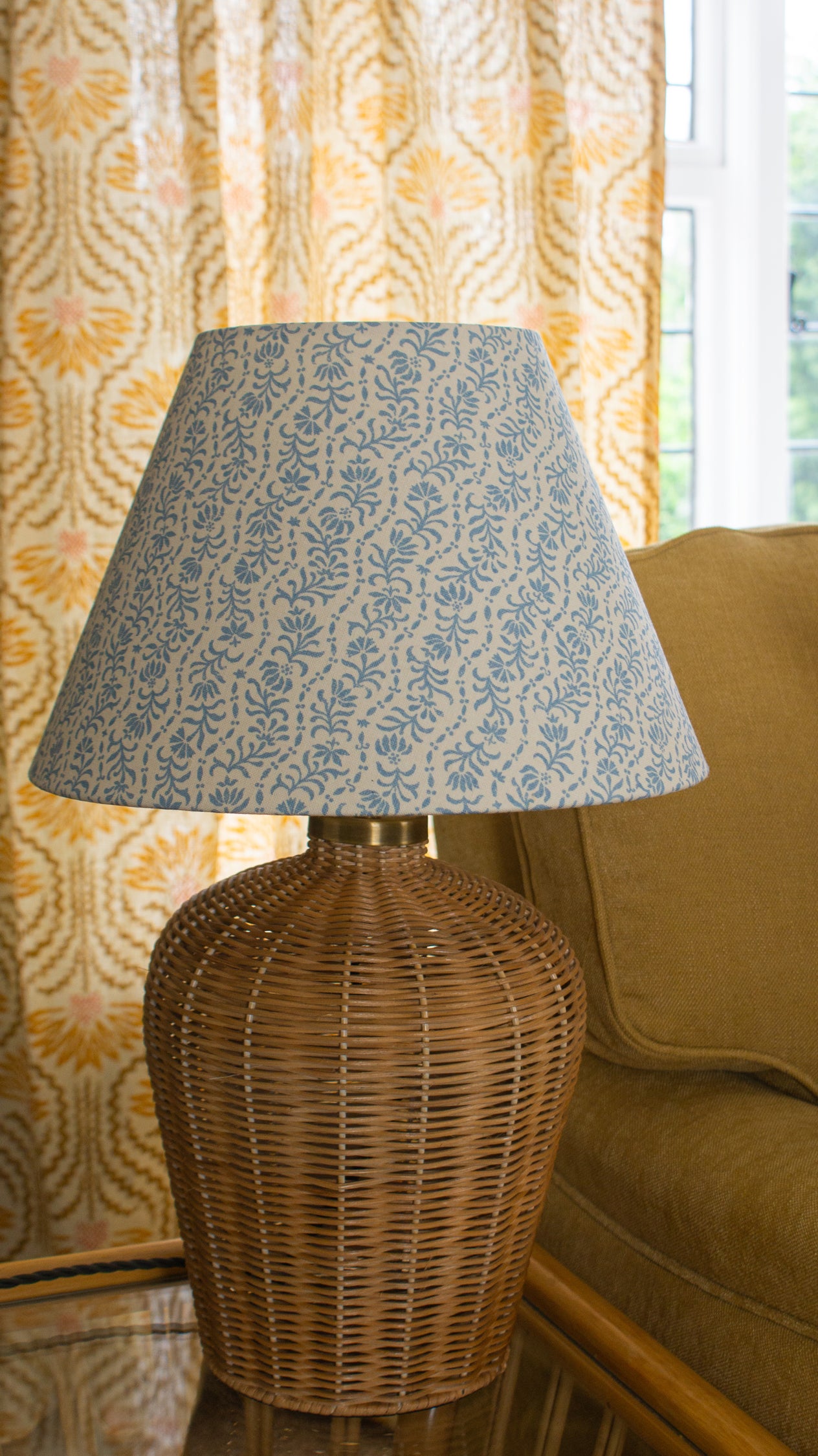Rattan table lamp with a blue and white floral stripe shade. 