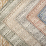 Stack of broadloom carpet samples in a textural herringbone design in a range of colors. 