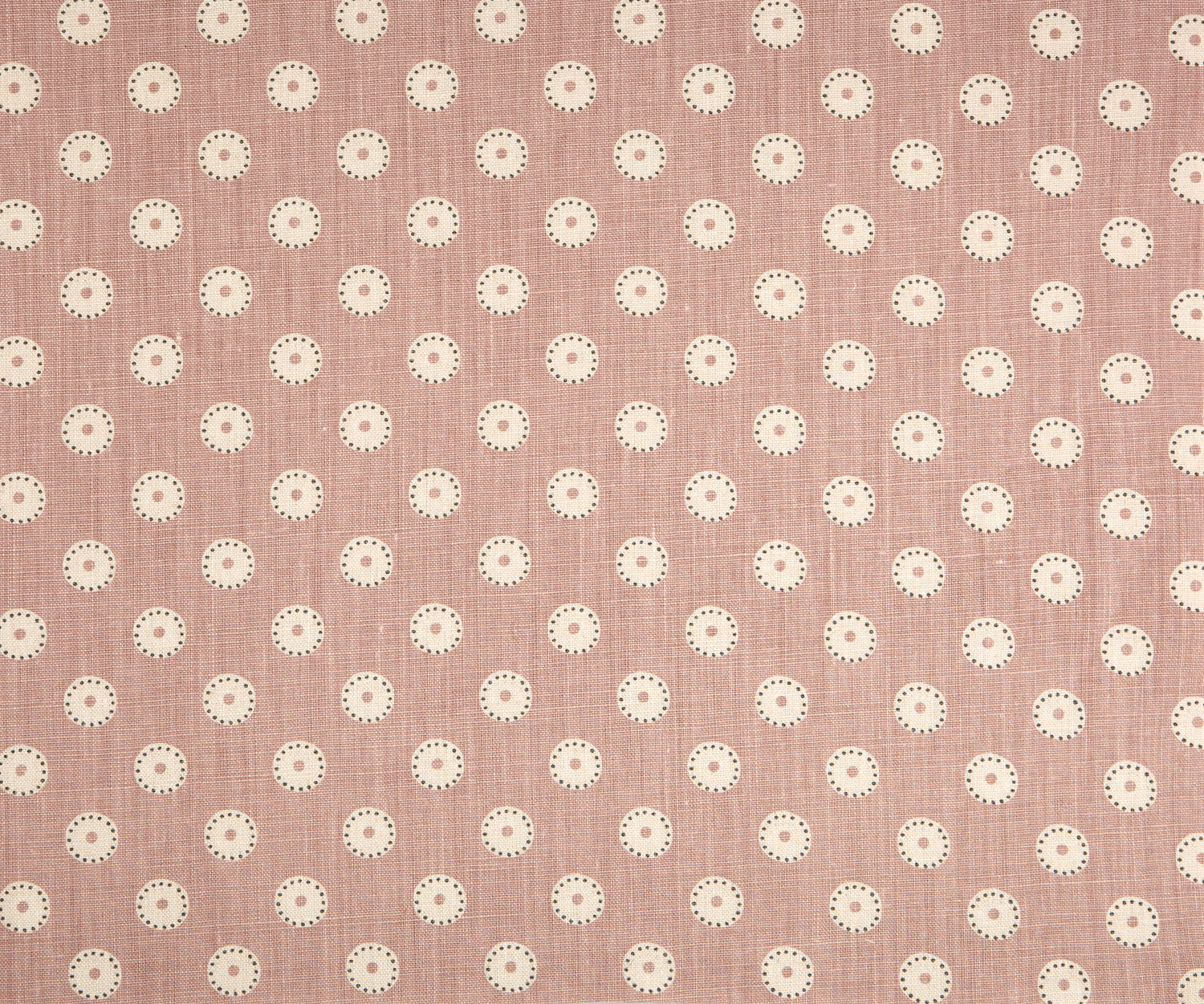 Detail of fabric in a playful dot print in gray and white on a mauve field.