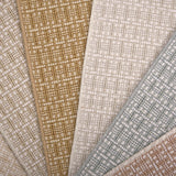 A close-up fan arrangement of basketweave pattern carpet samples in beige, tan, cream, light blue-gray, and dusty rose tones.