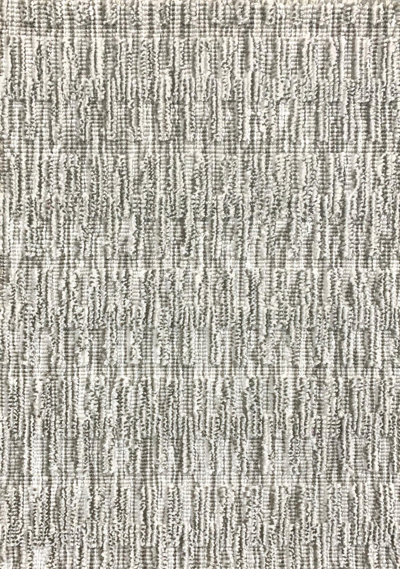 A close-up of a broadloom rug in a vertical ribbed pattern  in a neutral mix of off-white, and gray. 
