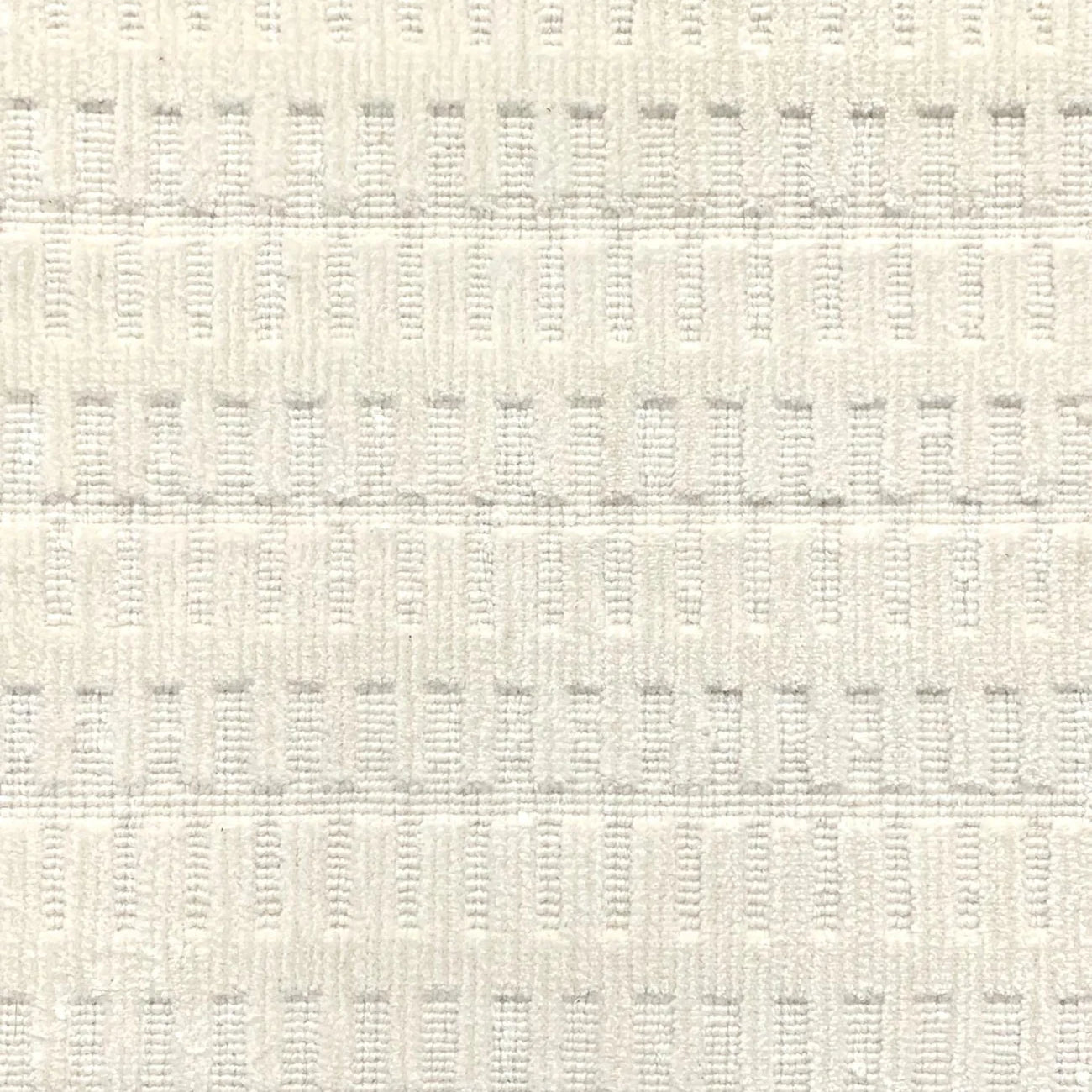 A close-up of a broadloom rug in a vertical ribbed pattern  in off-white.