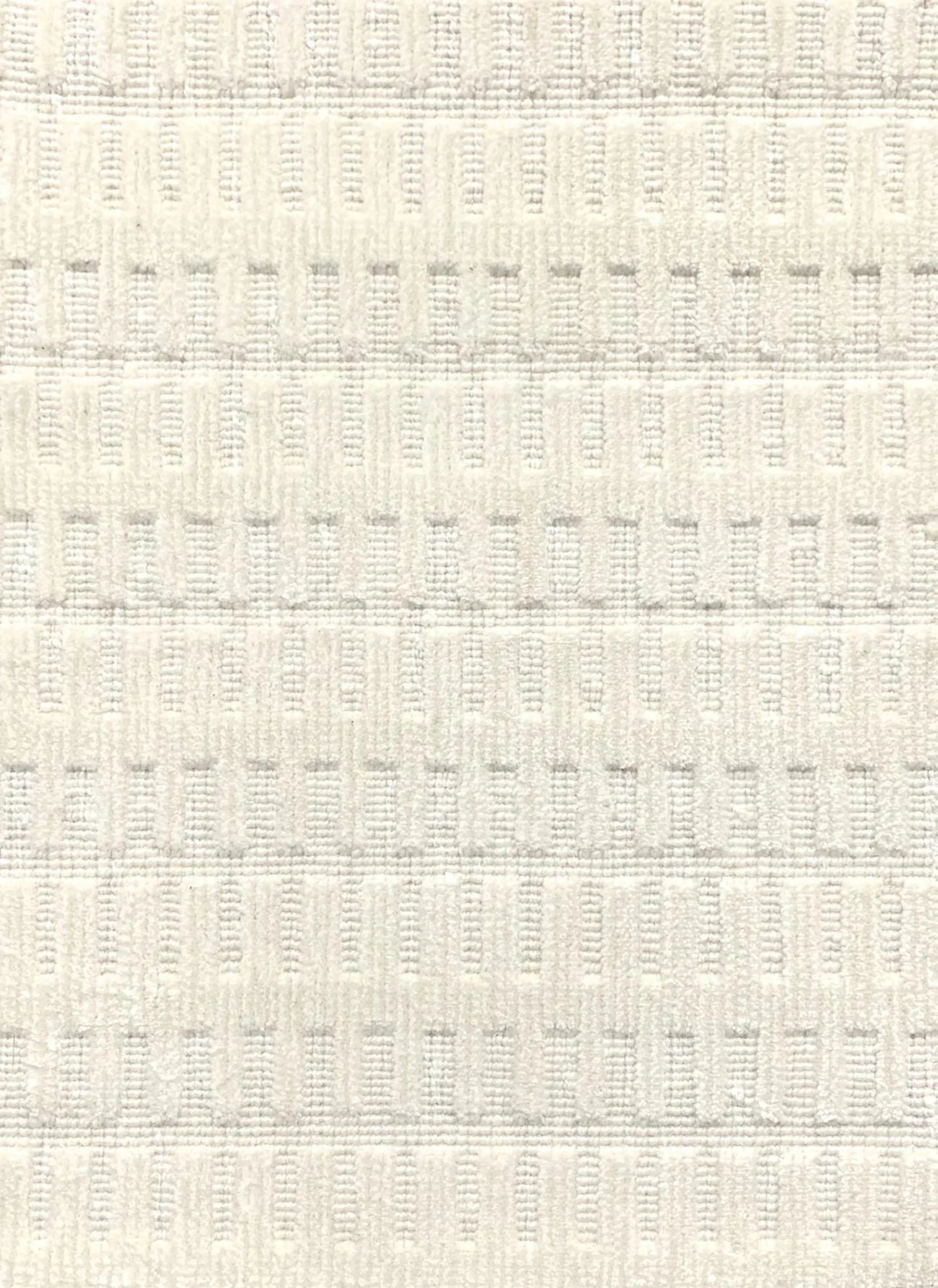 A close-up of a broadloom rug in a vertical ribbed pattern  in off-white.