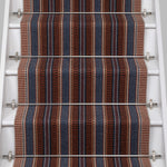 White stair case with a complex woven striped runner made of wool in shades of blue and red. 