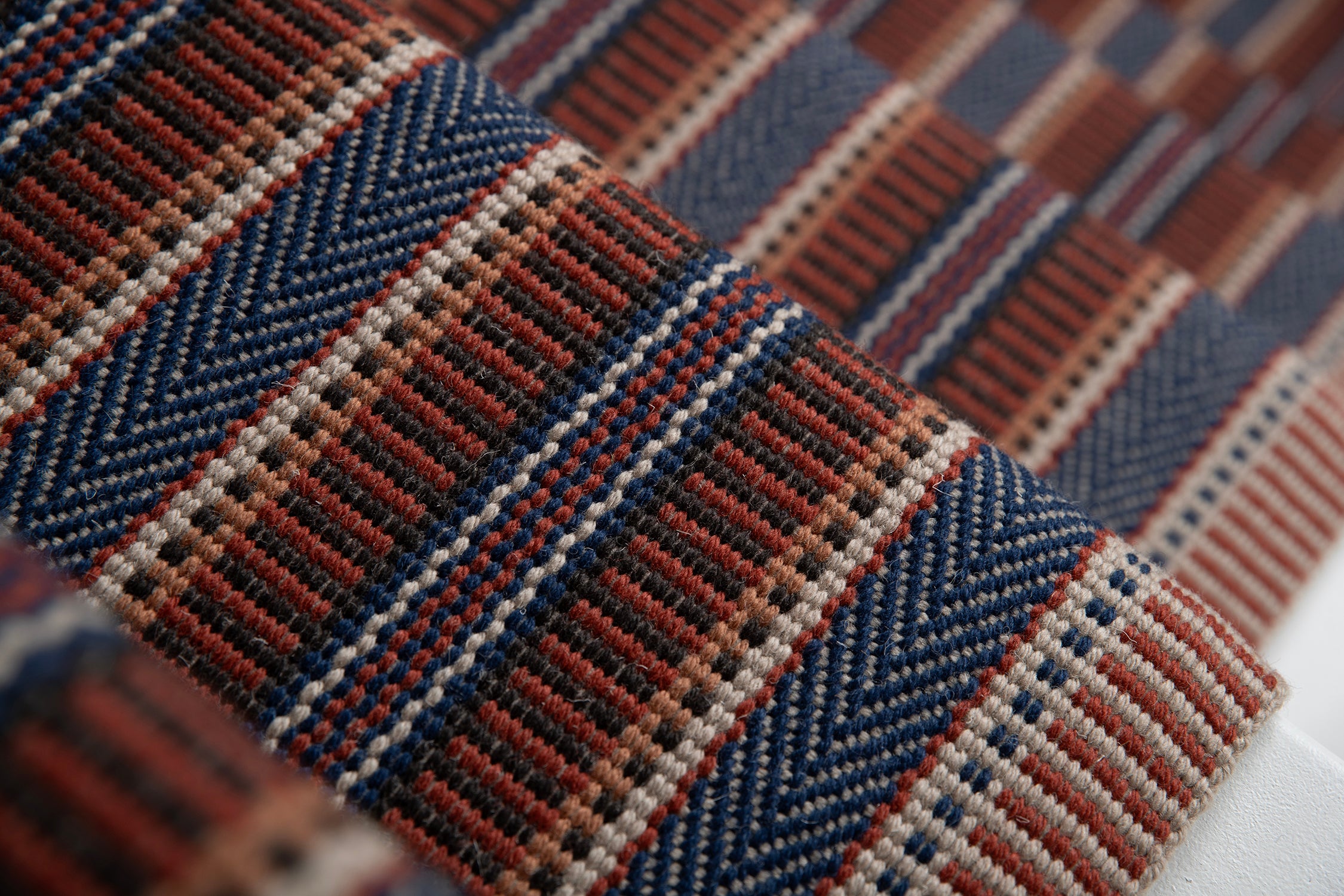 Detail of a complex woven striped runner made of wool in shades of blue and red. 