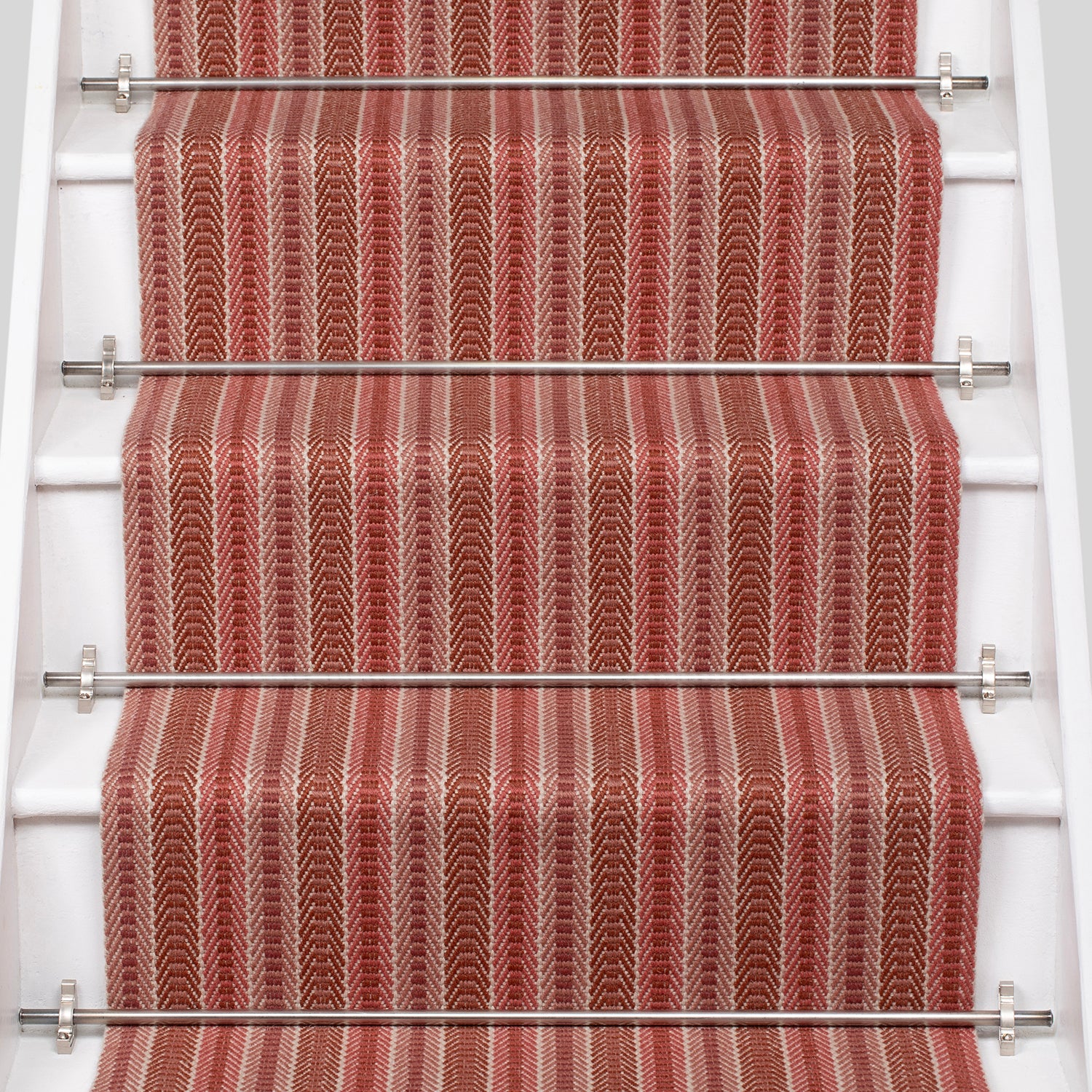 White staircase with a runner in a complex woven striped runner made of wool in shades of red.