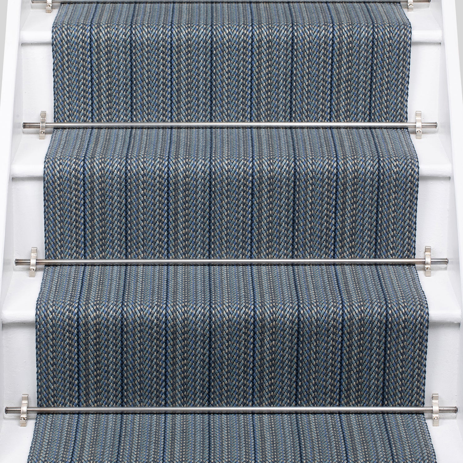 A close-up view of a staircase with carpeted steps in a blue-gray stripe pattern, bordered by white risers,