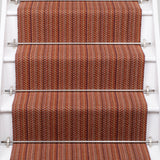A close-up view of a staircase with carpeted steps in a red-orange stripe pattern, bordered by white risers.