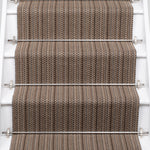 A close-up view of a staircase with carpeted steps in a taupe-brown stripe pattern, bordered by white risers