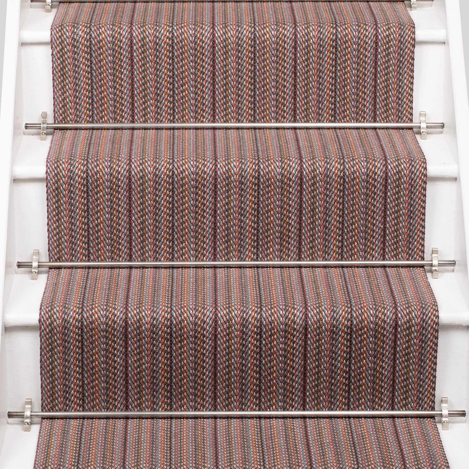 A close-up view of a staircase with carpeted steps in a pink-brown-blue stripe pattern, bordered by white risers