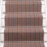 A close-up view of a staircase with carpeted steps in a pink-brown-blue stripe pattern, bordered by white risers