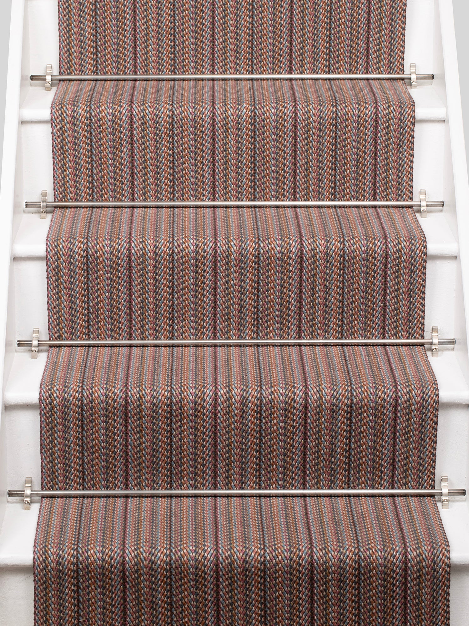 A close-up view of a staircase with carpeted steps in a pink-brown-blue stripe pattern, bordered by white risers