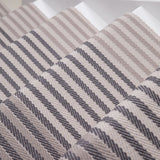 Close-up of a flatweave stair runner striped pattern in beige, taupe, and dark gray.