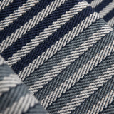 Close-up of a stair runner with a diagonal herringbone stripe in navy blue, steel blue and grey.