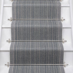 White stairs with textural striped runner in slate gray and blue with metal stair rails. 