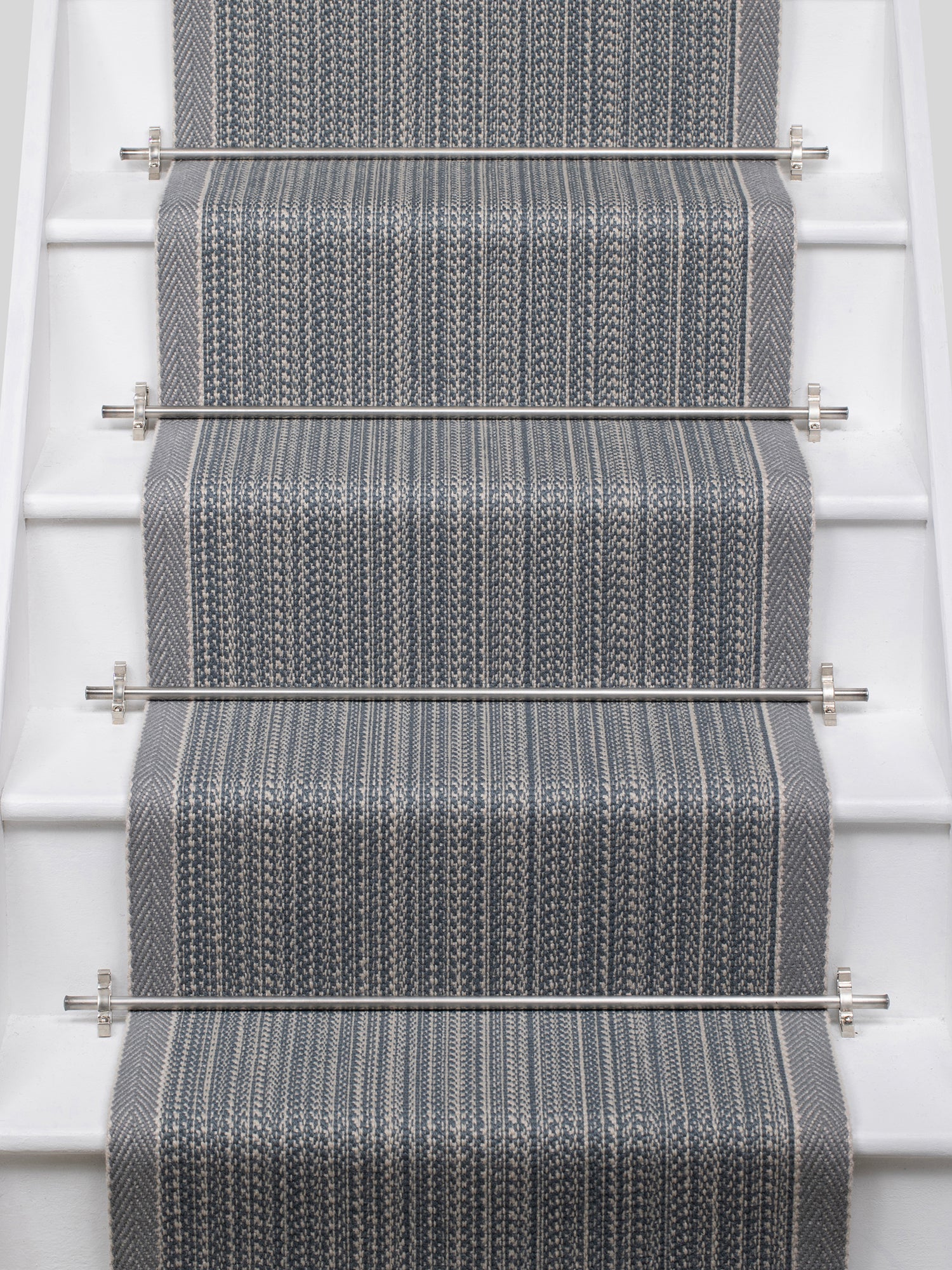 White stairs with textural striped runner in slate gray and blue with metal stair rails. 
