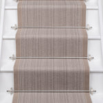 White stairs with textural striped runner in warm beige with metal stair rails. 