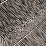 Close-up of a textured stair runner in a heathered gray and black woven pattern, showing the ribbed steps and a metal rail. 