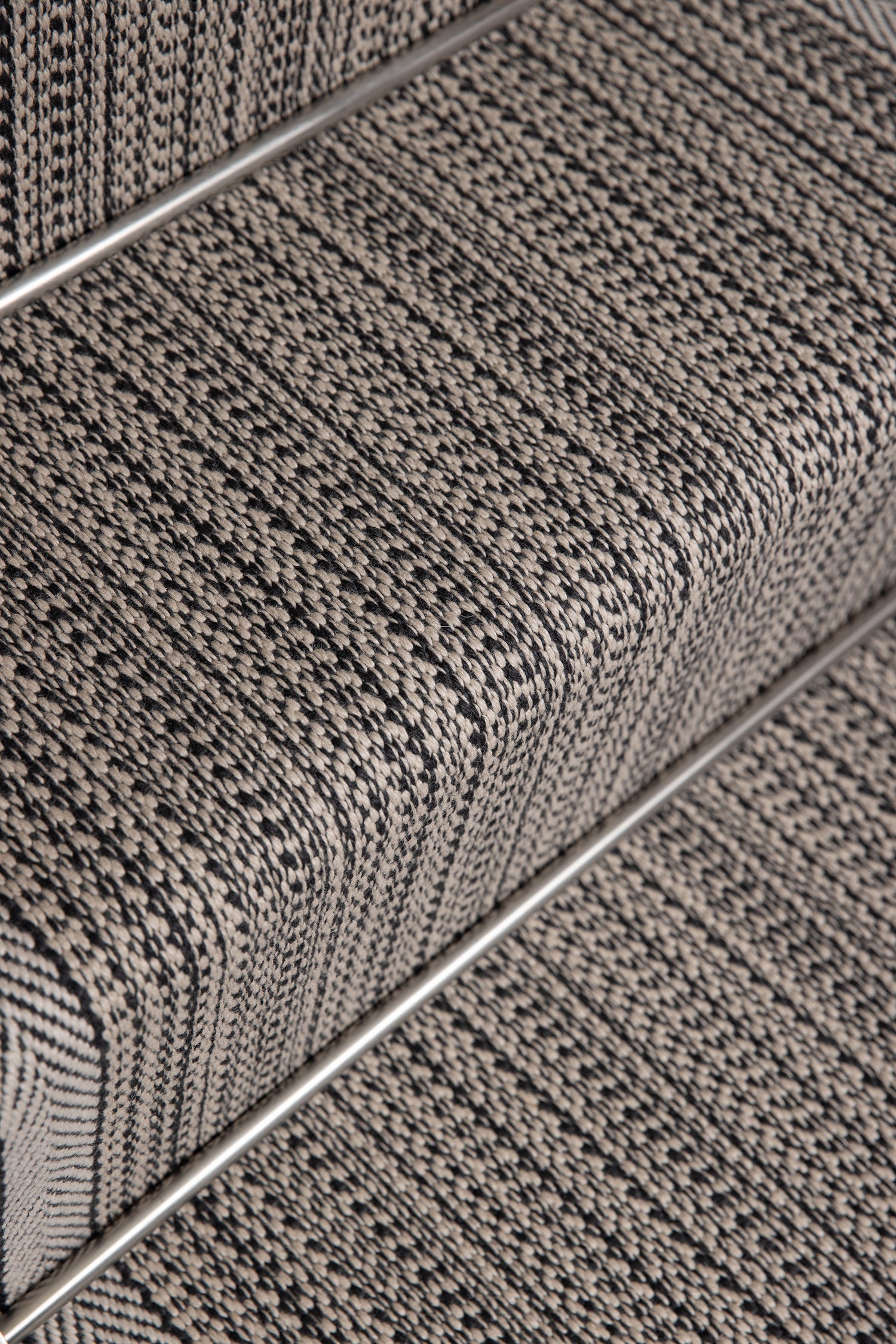 Close-up of a textured stair runner in a heathered gray and black woven pattern, showing the ribbed steps and a metal rail. 