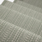 A close-up of a stair runner sample in a muted sage green color textural stripe.
