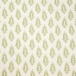 Detail of fabric in a repeating leaf pattern in light green on a cream field.