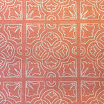 Detail of fabric in a damask lattice print in white on a coral field.