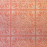 Detail of fabric in a damask lattice print in white on a coral field.