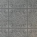 Detail of fabric in a damask lattice print in light gray on a gray field.