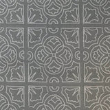 Detail of fabric in a damask lattice print in light gray on a gray field.