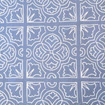 Detail of fabric in a damask lattice print in white on a blue field.