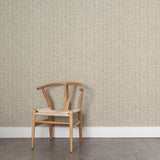 A wooden chair stands in front of a wall papered in a small-scale checked pattern in shades of cream and gray.