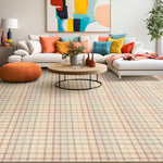 Living room interior with a white couch with brightly colored throw pillows atop a plaid area rug.