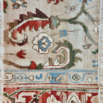 Handknotted rug sample in an traditional pattern in red, taupe, green, blue and ivory.