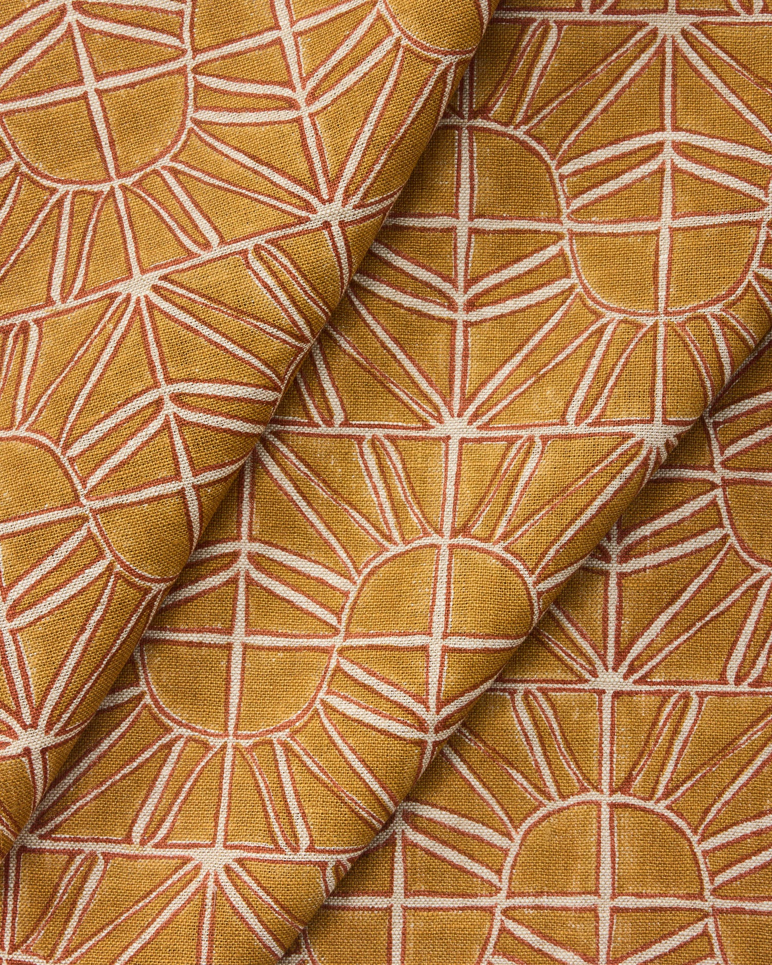 Draped fabric with geometric sun pattern in warm yellow and rust.