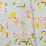 Folded linen swatch with a pattern of large-scale line-drawn flowers in gray ink with red, pink and yellow watercolors, on a light blue background.