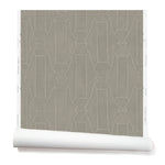 Partially unrolled wallpaper in a repeating curvolinear print in white on a painted gray field.
