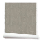 Partially unrolled wallpaper in a repeating curvolinear print in white on a painted gray field.