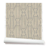 Partially unrolled wallpaper in a repeating curvolinear print in navy on a painted tan field.