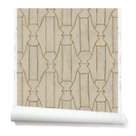 Partially unrolled wallpaper in a repeating curvolinear print in rust on a painted cream field.