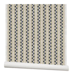 Partially unrolled wallpaper in a repeating mosaic stripe print in shades of green and gray-blue on a tan field.