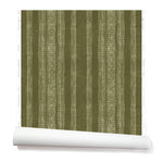 A partially unrolled roll of wallpaper in a striped pattern of intricate white lines over a deep olive green background.