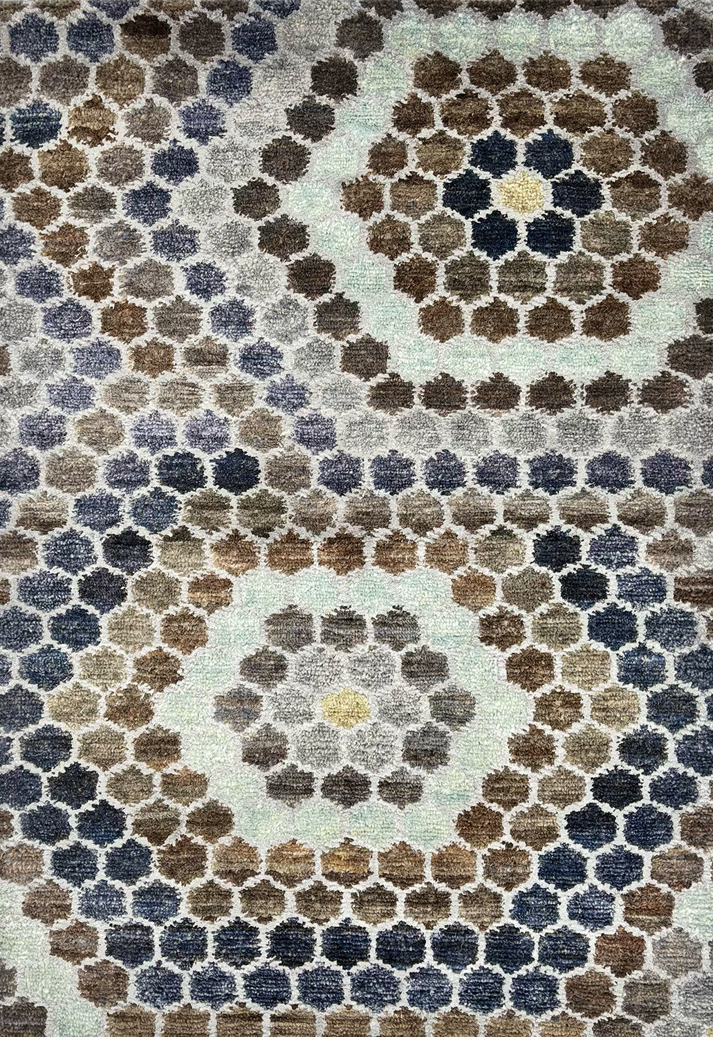 Detail of a handknotted rug with a classic hexagon pattern in shades of blue, grey, white and indigo. 