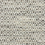 Detail of a handowven rug in an diamond like pattern in white and beige with grey accents.